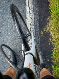 The legs of a person standing over a white Fairlight Strael bicycle