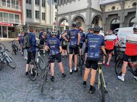 A group of riders in their dark blue Rad-Treff-Borchen jerseys standing with their bicycles in front of the Paderborn city hall