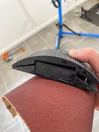 A sanding block with a piece of sanding paper hold in hand