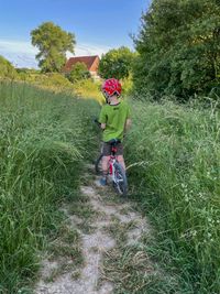 Emil with his strawberry helmet and his red Woom bike in high green grass