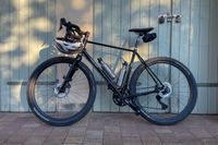 A black Fairlight Secan Gravel bike leaning to a wooden door in the warm evening sun.