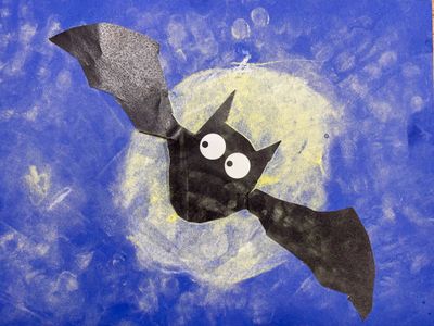 A friendly black bat with big white eyes in front of a dark blue background