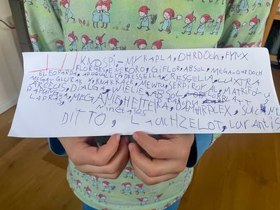 Emil holding a paper strip with the names of many pokemons written very dense.
