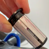 A hand holding the compression bung which is covered with carbon fitting paste