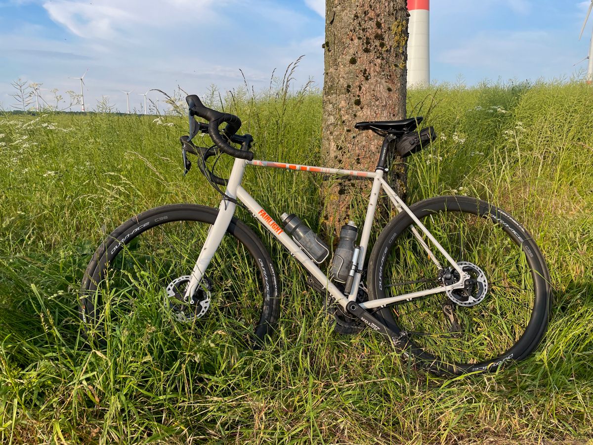 A white Strael 3.0 bicycle leant at a tree.