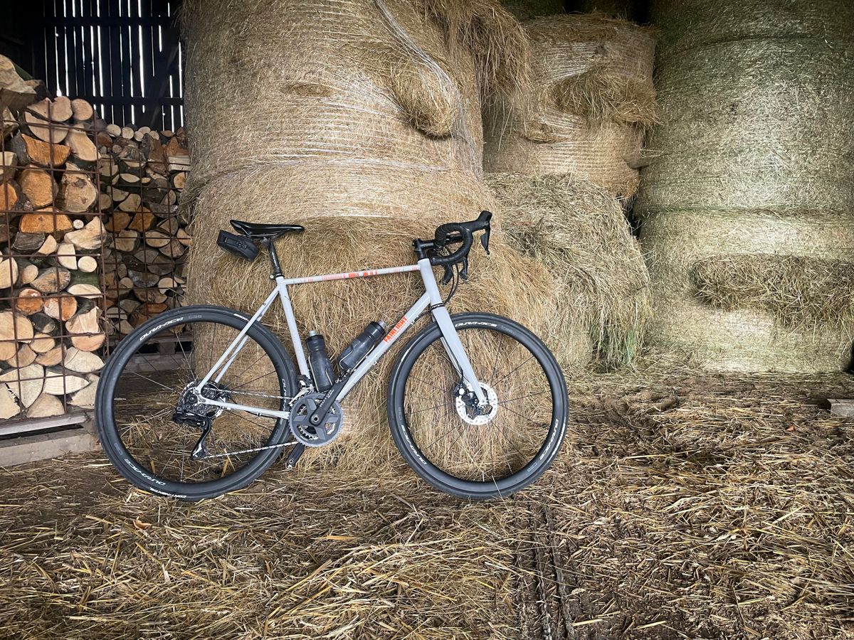 The white Strael biciycle in a shed in front of big hay rolls.