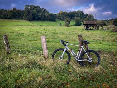 My white Strael steel race bike leaning at a fence in front of a meadow with a shed in the background.