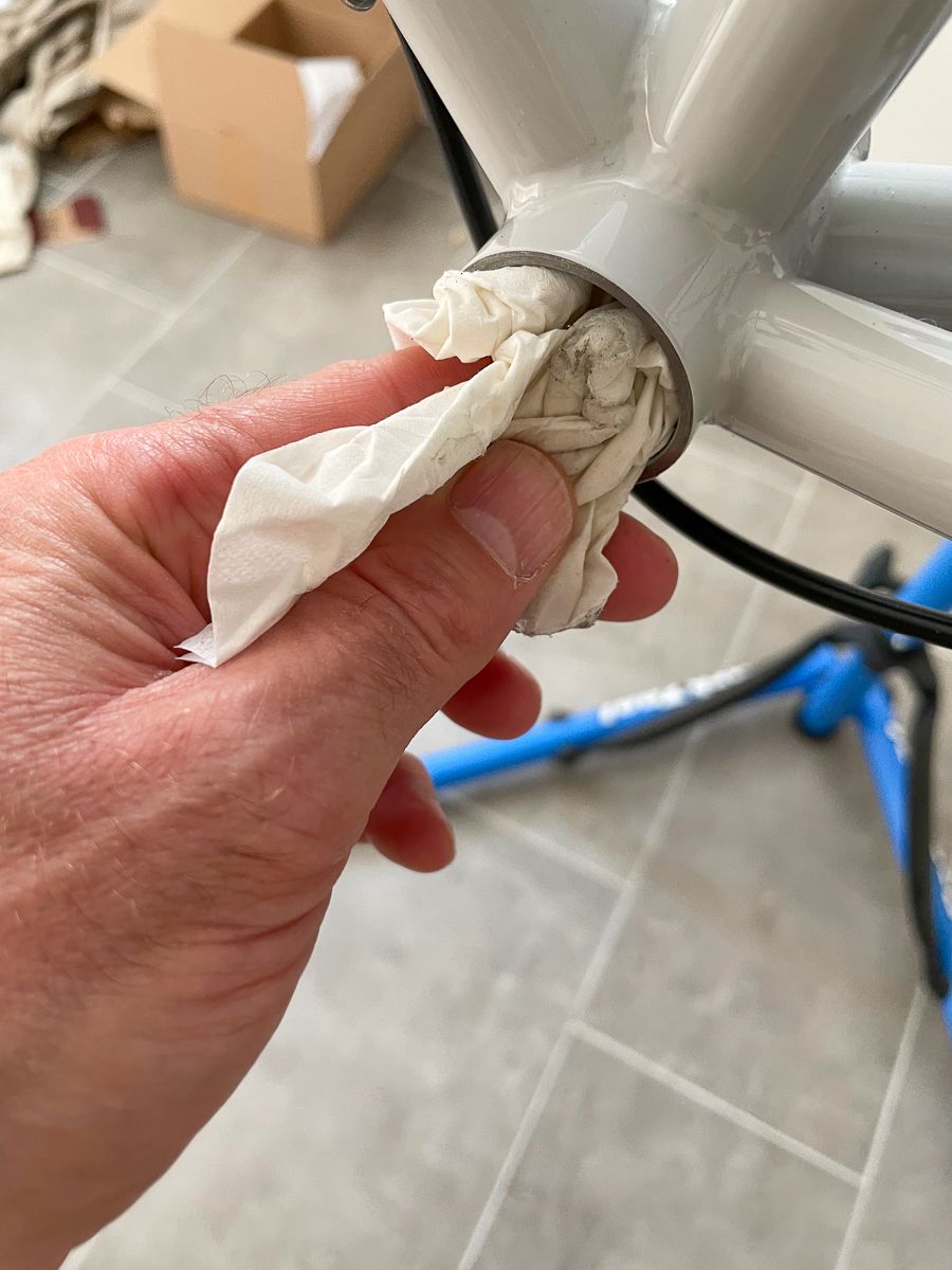 A hand with a paper tower cleaning the bottom bracket shell