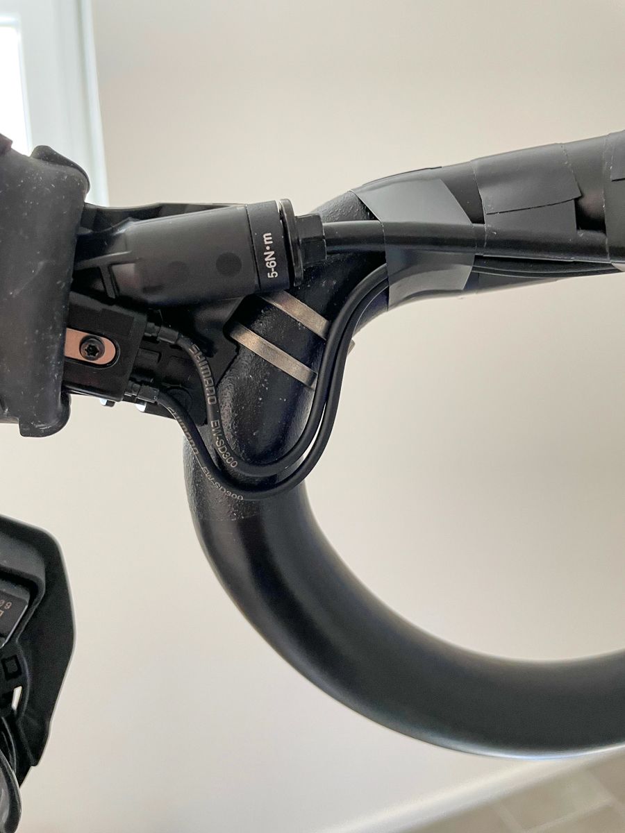 A Shimano Dual Control Shifter with removed rubber hood so that the ingoing Di2 wire is visible. The wire doesn´t go straight into the shifter but with a 2 cm loop.