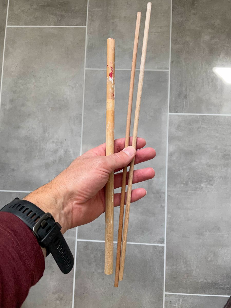 A hand holding three thin sticks