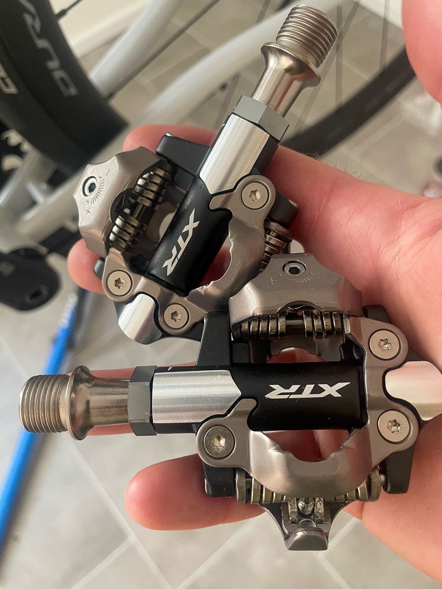 A hand holding two Shimano XTR pedals